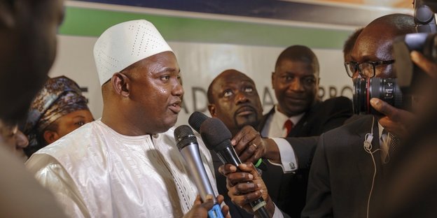 Der gambische Präsident Adama Barrow in weißer Kleidung, er wird von vielen Journalisten interviewt Der gambische Präsident Adama Barrow in weißer Kleidung, er wird von vielen Journalisten interviewt