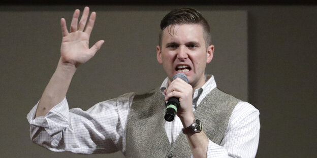 Der Anführer der Alt-Right-Bewegung mit einer erhobenen Hand und einem Mikrofon in der anderen Der Anführer der Alt-Right-Bewegung mit einer erhobenen Hand und einem Mikrofon in der anderen