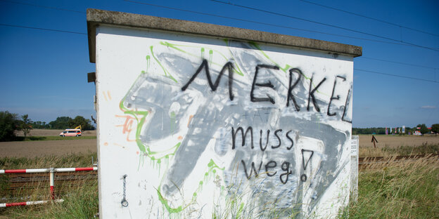 An einer Betonwand vor einer Wiesenlandschaft steht der Schriftzug "Merkel muss weg" An einer Betonwand vor einer Wiesenlandschaft steht der Schriftzug "Merkel muss weg"