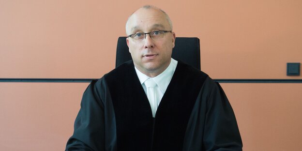 Richter Jens Maier sitzt an einem Pult und blickt in die Kamera
