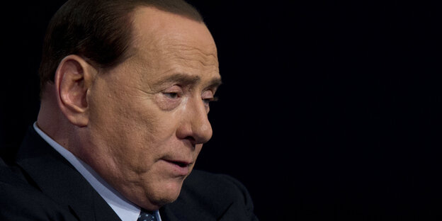 Berlusconi in schwarzem Jackett vor schwarzem Hintergrund guckt sorgenvoll Berlusconi in schwarzem Jackett vor schwarzem Hintergrund guckt sorgenvoll