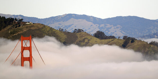 Ein roter Pfeiler der Golden Gate Bridge ragt aus einem dicken weißen Wolkenteppich Ein roter Pfeiler der Golden Gate Bridge ragt aus einem dicken weißen Wolkenteppich