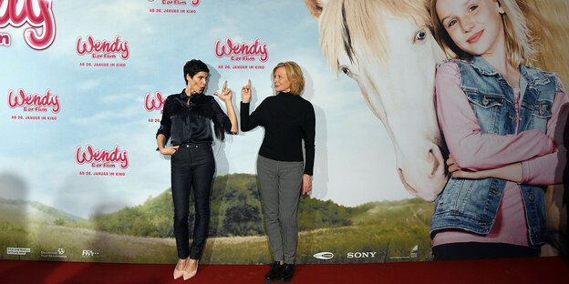 Zwei Frauen vor einem riesigen Filmplakat mit Mädchen und Pferd Zwei Frauen vor einem riesigen Filmplakat mit Mädchen und Pferd