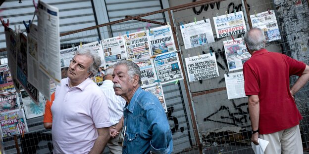 Griechische Männer lesen Zeitungen an einem Straßenstand Griechische Männer lesen Zeitungen an einem Straßenstand