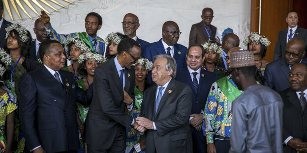 Männer in Anzügen und Frauen mit Blumen im Haar stehen als Pulk beim Gipfel der Afrikanischen Union herum Männer in Anzügen und Frauen mit Blumen im Haar stehen als Pulk beim Gipfel der Afrikanischen Union herum