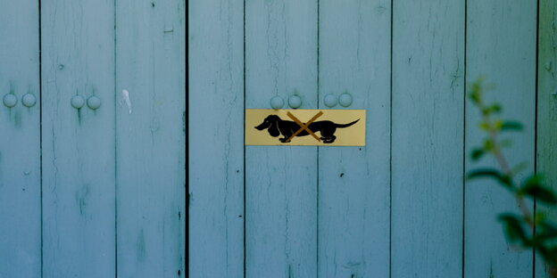 Auf einer blauen Holzwand ist ein Schild mit einem durchgestrichenen Dackel Auf einer blauen Holzwand ist ein Schild mit einem durchgestrichenen Dackel