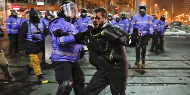 Ein Mann wird von einem Polizisten festgehalten Ein Mann wird von einem Polizisten festgehalten