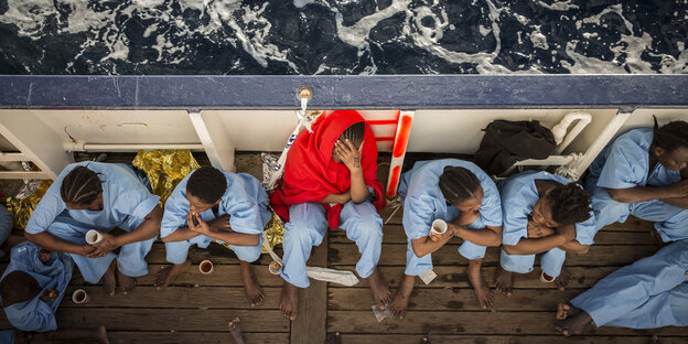 Frauen in blauer Kleidung sitzen an Deck eines Schiffes Frauen in blauer Kleidung sitzen an Deck eines Schiffes