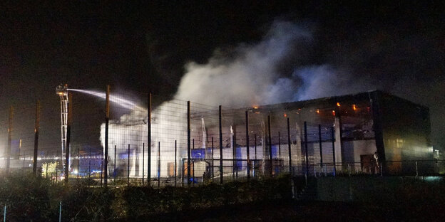 Feuerwehrleute löschen ein brennendes Gebäude Feuerwehrleute löschen ein brennendes Gebäude
