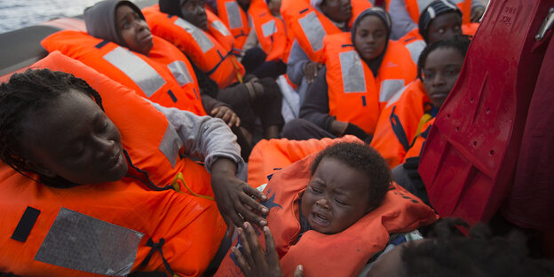 Flüchtlinge in Schwimmwesten an Deck eines Schiffes Flüchtlinge in Schwimmwesten an Deck eines Schiffes