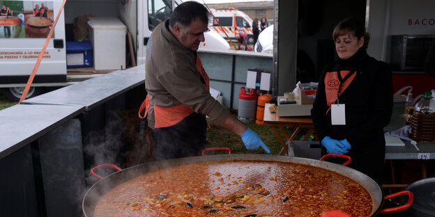Zwei Leute vor einer großen Pfanne Paella Zwei Leute vor einer großen Pfanne Paella