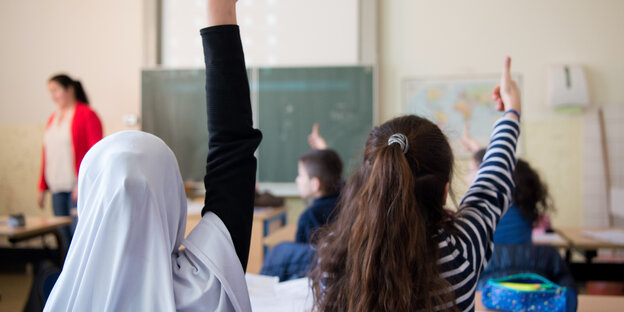 Zwei Mädchen zeigen in der Schule auf Zwei Mädchen zeigen in der Schule auf