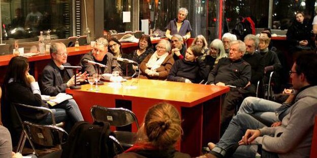 Ein Tisch im taz Café und Menschen, die darum herum sitzen Ein Tisch im taz Café und Menschen, die darum herum sitzen