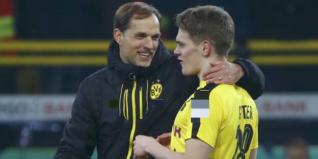 Ein Fußballtrainer legt seinen Arm um einen Spieler und spricht mit ihm Ein Fußballtrainer legt seinen Arm um einen Spieler und spricht mit ihm