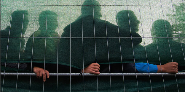 Hinter einem Zaun warten Flüchtlinge Hinter einem Zaun warten Flüchtlinge
