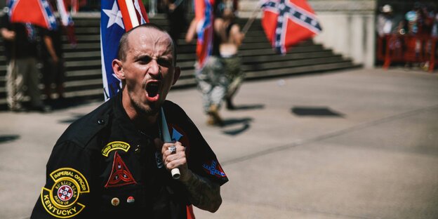 Ein brüllender Mann hält eine Flagge über seine Schulter Ein brüllender Mann hält eine Flagge über seine Schulter