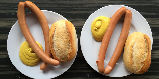 Zwei Paar Wiener Würstchen mit Senf und Brot liegen auf einem Teller Zwei Paar Wiener Würstchen mit Senf und Brot liegen auf einem Teller