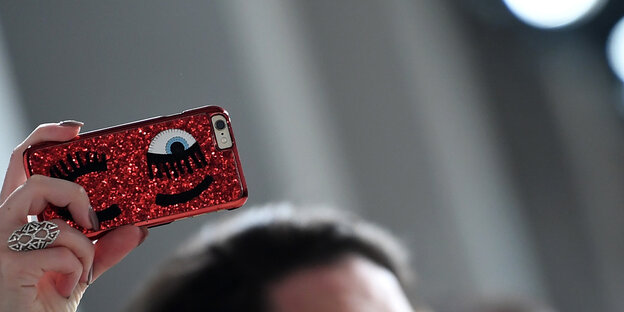 Eine Hand hält ein rotes Handy in die Höhe Eine Hand hält ein rotes Handy in die Höhe
