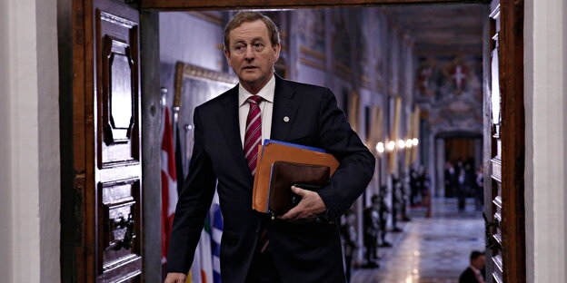 Der irische Premier Enda Kenny geht mit einem Ordner unterm Arm durch eine Tür Der irische Premier Enda Kenny geht mit einem Ordner unterm Arm durch eine Tür