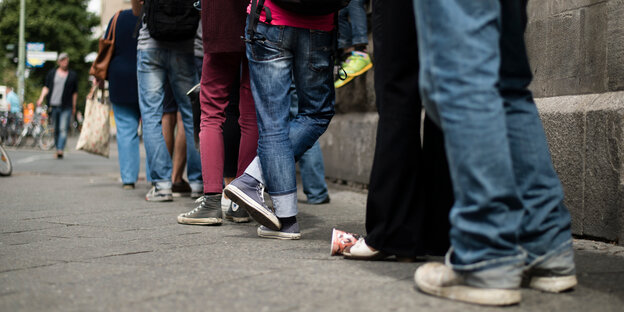 Beine von Menschen, die in einer Schlange warten Beine von Menschen, die in einer Schlange warten