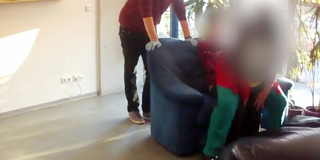 Frau sitzt auf dem Schoß einer anderen Frau, die sie fast komplett verdeckt Frau sitzt auf dem Schoß einer anderen Frau, die sie fast komplett verdeckt