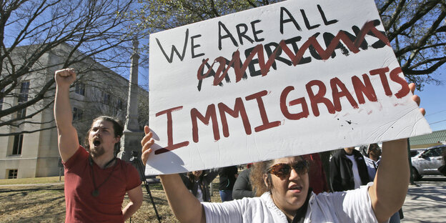 Eine Demonstrantin hält ein Schild hoch: "we are all immigrants" steht darauf, ein "Americans" ist durchgestrichen Eine Demonstrantin hält ein Schild hoch: "we are all immigrants" steht darauf, ein "Americans" ist durchgestrichen