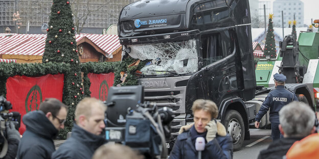 Der Lkw, mit dem der Anschlag von Breitscheidplatz verübt wurde steht mit zersplitterter Frontscheibe auf dem Weihnachtsmarkt, drum herum telefonieren hektisch Polizisten Der Lkw, mit dem der Anschlag von Breitscheidplatz verübt wurde steht mit zersplitterter Frontscheibe auf dem Weihnachtsmarkt, drum herum telefonieren hektisch Polizisten