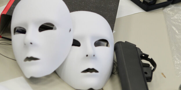 zwei weiße Theatermasken liegen auf einem Aktenordner zwei weiße Theatermasken liegen auf einem Aktenordner