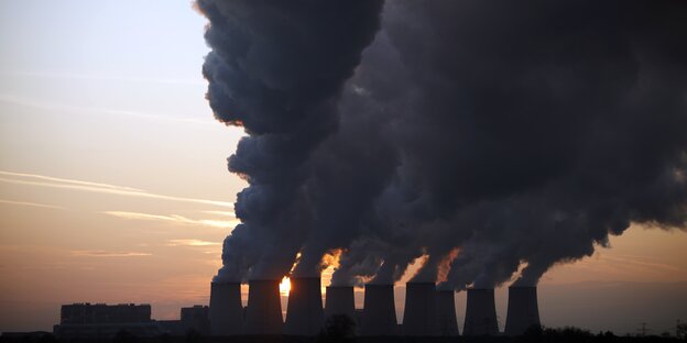 Große Industrieanlage mit Riesenschornsteinen, aus denen Dampfwolken steigen Große Industrieanlage mit Riesenschornsteinen, aus denen Dampfwolken steigen