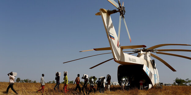 Menschen entladen aus einem Hubschrauber Pakete