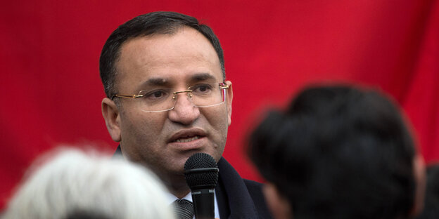 Der türkische Justizminister Bekir Bozdag mit Mikro vor rotem Hintergrund Der türkische Justizminister Bekir Bozdag mit Mikro vor rotem Hintergrund