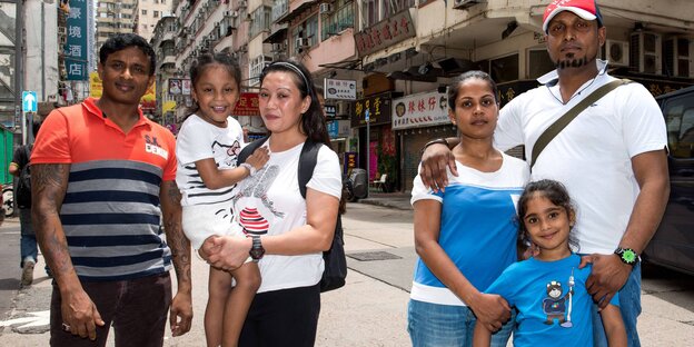 Zwei Männer, zwei Frauen und zwei Kinder stehen auf einer Straße