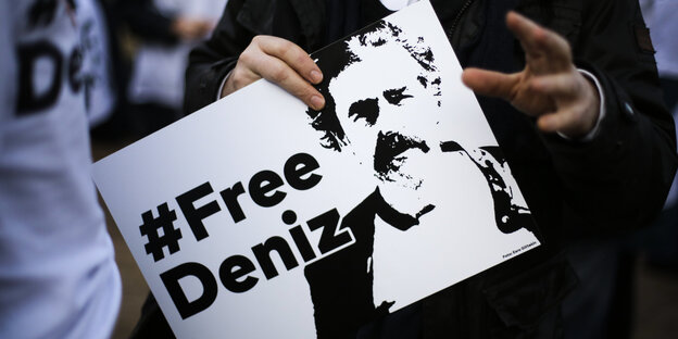 Ein Mensch hält ein Schild, auf dem „#Free Deniz“ steht Ein Mensch hält ein Schild, auf dem „#Free Deniz“ steht