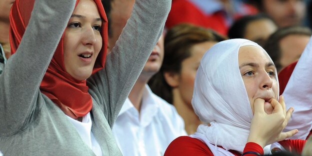 Frauen im Kopftuch jubeln auf der Tribüne den Basketball-Spielerinnen zu Frauen im Kopftuch jubeln auf der Tribüne den Basketball-Spielerinnen zu