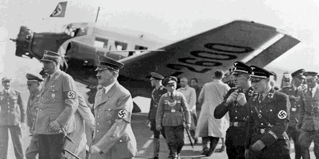 Hitler und weitere Nazis vor einem Flugzeug in schwarz-weiß Hitler und weitere Nazis vor einem Flugzeug in schwarz-weiß