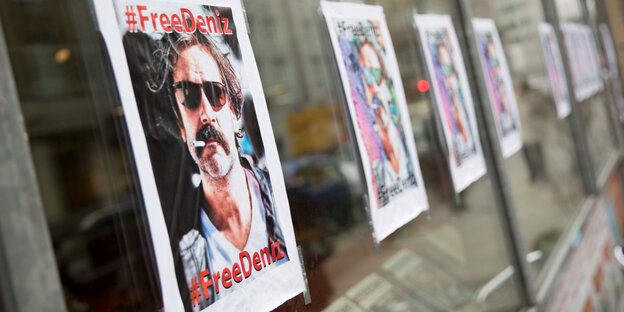 An einer Fensterscheibe hängen Poster mit dem Porträt von Deniz Yücel An einer Fensterscheibe hängen Poster mit dem Porträt von Deniz Yücel