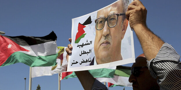 Demonstranten halten die jordanische Flagge und ein Banner mit dem Gesicht des ermordeten Nahed Hattar in die Höhe Demonstranten halten die jordanische Flagge und ein Banner mit dem Gesicht des ermordeten Nahed Hattar in die Höhe