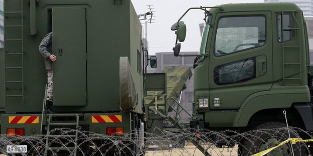 Ein Mensch betritt ein großes Fahrzeug, hinter dem eine Rakete stationiert ist Ein Mensch betritt ein großes Fahrzeug, hinter dem eine Rakete stationiert ist