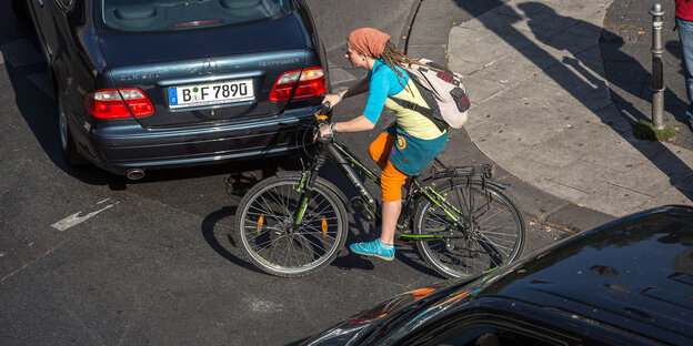 Eine Radfahrerin zwischen zwei Autos Eine Radfahrerin zwischen zwei Autos
