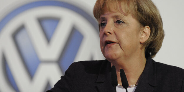 Angela Merkel spricht vor einem großen VW Zeichen auf einer Veranstaltung des Autokonzern Angela Merkel spricht vor einem großen VW Zeichen auf einer Veranstaltung des Autokonzern