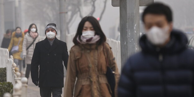 Viele chinesische Passanten laufen im nebliger Umgebung mit Atemschutzmasken Viele chinesische Passanten laufen im nebliger Umgebung mit Atemschutzmasken