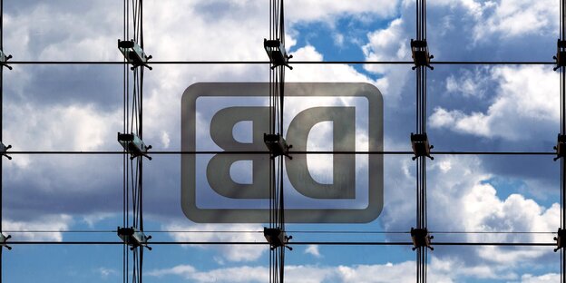 Spiegelverkehrtes Bahnlogo an Glasfassade vor leicht bedecktem Himmel Spiegelverkehrtes Bahnlogo an Glasfassade vor leicht bedecktem Himmel