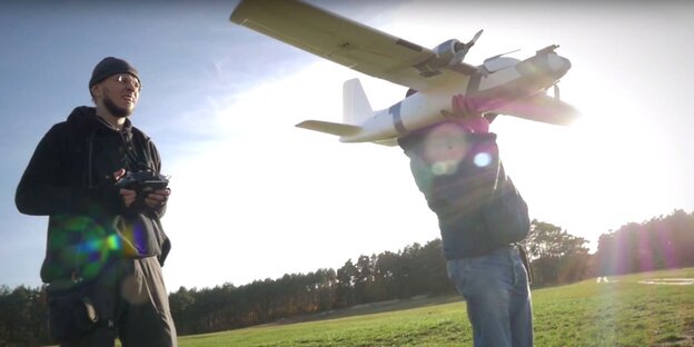 Zwei Männer starten eine Drohne, die wie ein kleines Flugzeug aussieht Zwei Männer starten eine Drohne, die wie ein kleines Flugzeug aussieht