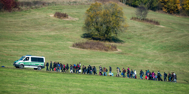 Menschen gehen in langer Schlange hinter einem Polizeifahrzeug her Menschen gehen in langer Schlange hinter einem Polizeifahrzeug her