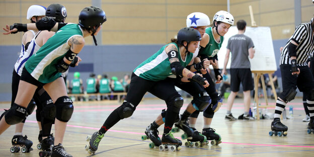 Sportlerinnen der Riot Rocketz fahren in einer Turnhalle mit Rollschuhen Sportlerinnen der Riot Rocketz fahren in einer Turnhalle mit Rollschuhen