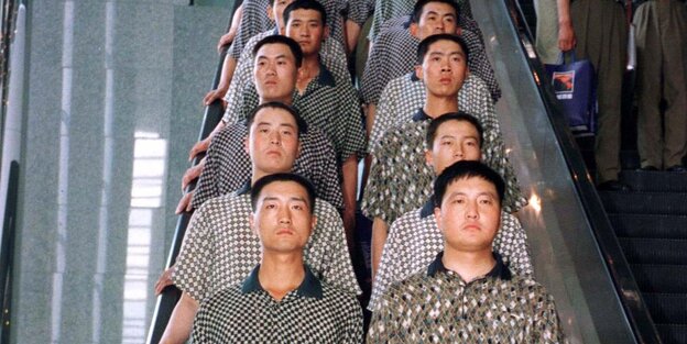 sehr ähnlich gekleidete Menschen in Zweierreihe auf einer Rolltreppe sehr ähnlich gekleidete Menschen in Zweierreihe auf einer Rolltreppe