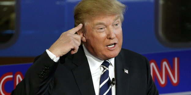 Donald Trump hält eine Rede und hält sich den Zeigefinger an die Schläfe Donald Trump hält eine Rede und hält sich den Zeigefinger an die Schläfe