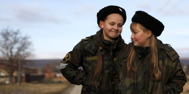 zwei jugendliche Mädchen in Uniform grinsen sich an zwei jugendliche Mädchen in Uniform grinsen sich an