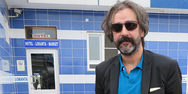 Deniz Yücel steht mit Sonnenbrille und Jacket vor einem Gebäude Deniz Yücel steht mit Sonnenbrille und Jacket vor einem Gebäude