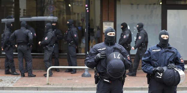 Polizisten in Montur stehen vor einem Gebäude Polizisten in Montur stehen vor einem Gebäude